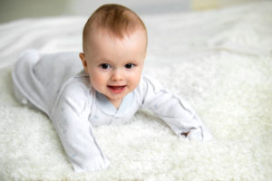 Baby liegt auf kuscheligem Teppich
